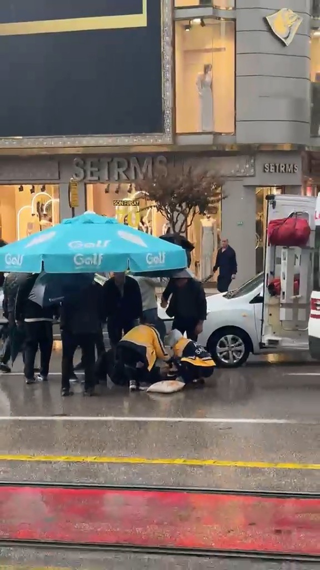 Bursa Osmangazi'de otomobil yayaya çarptı, çevredekiler yağmurda şemsiye tuttu