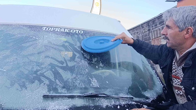 Sürücüler Kars'ta eksi 6 derecede buz tutan araç camlarını kazıyarak temizledi